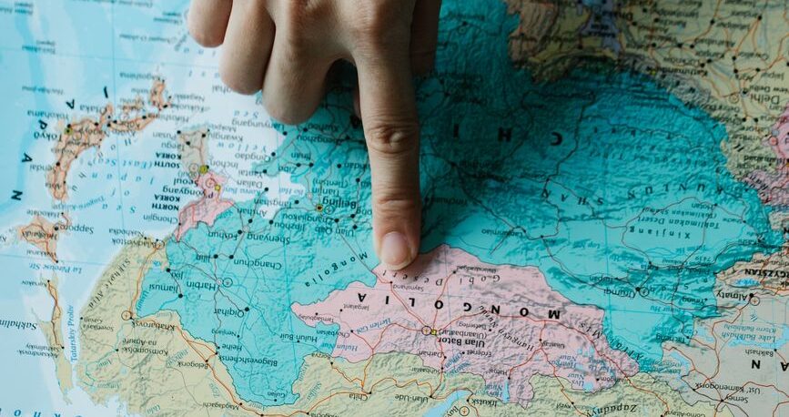 female hand pointing mongolia on a political map
