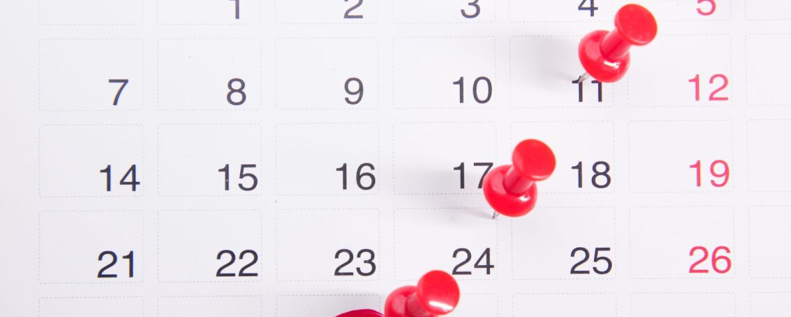 close up photo of red pins on a calendar